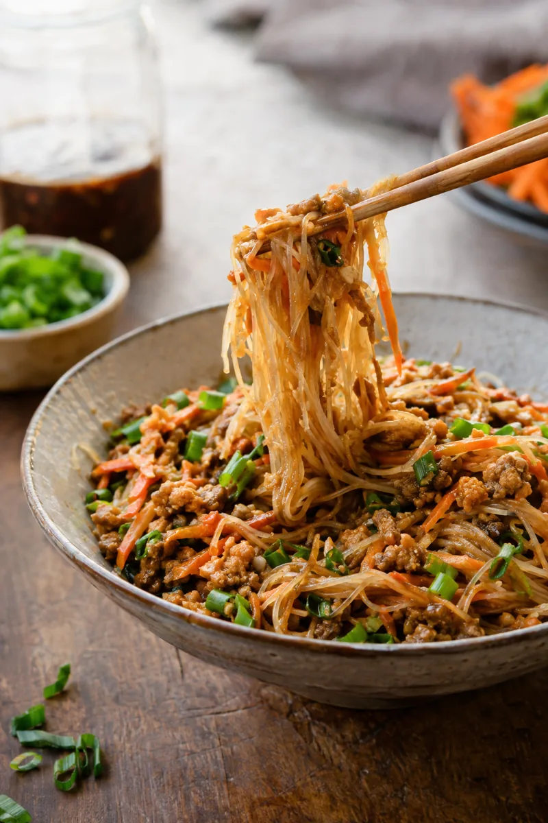 plate of ground chicken rice noodles with chopsticks