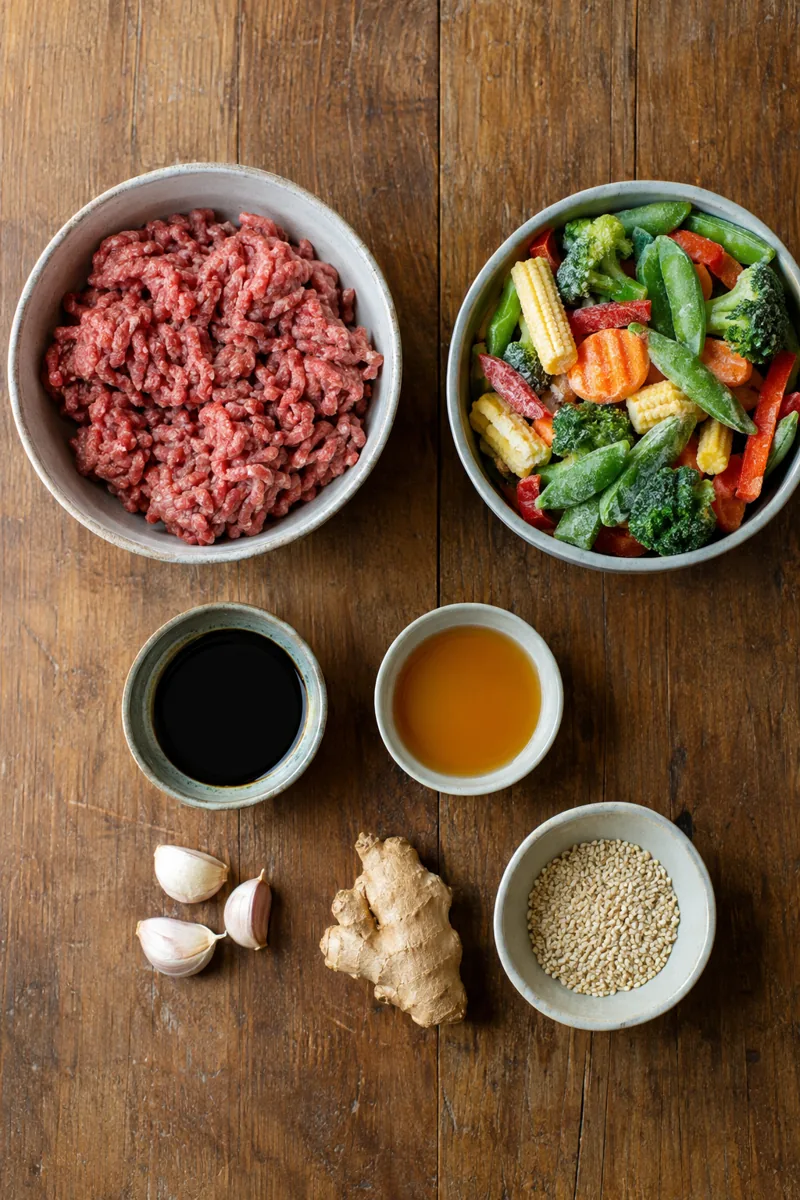 Ingredients laid out: ground beef, frozen stir fry vegetables, soy sauce, honey, garlic, ginger and sesame seeds